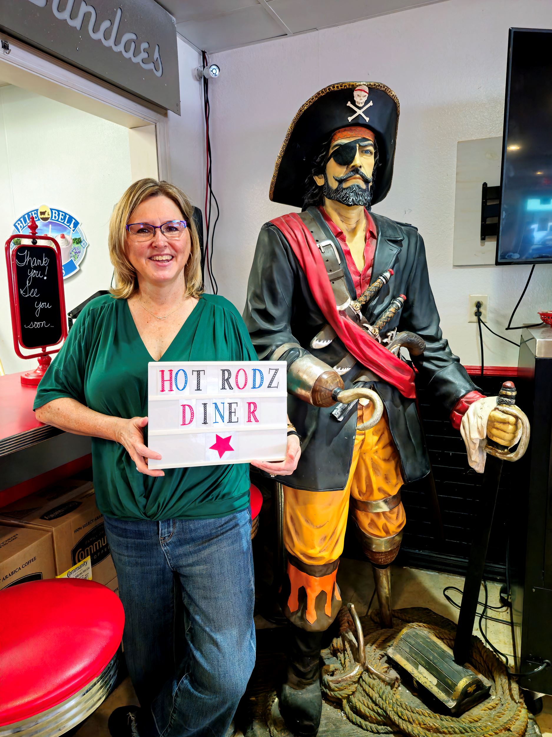 Kathy Lawson, owner of Hot Rodz Diner, stands next to pirate holding a sign