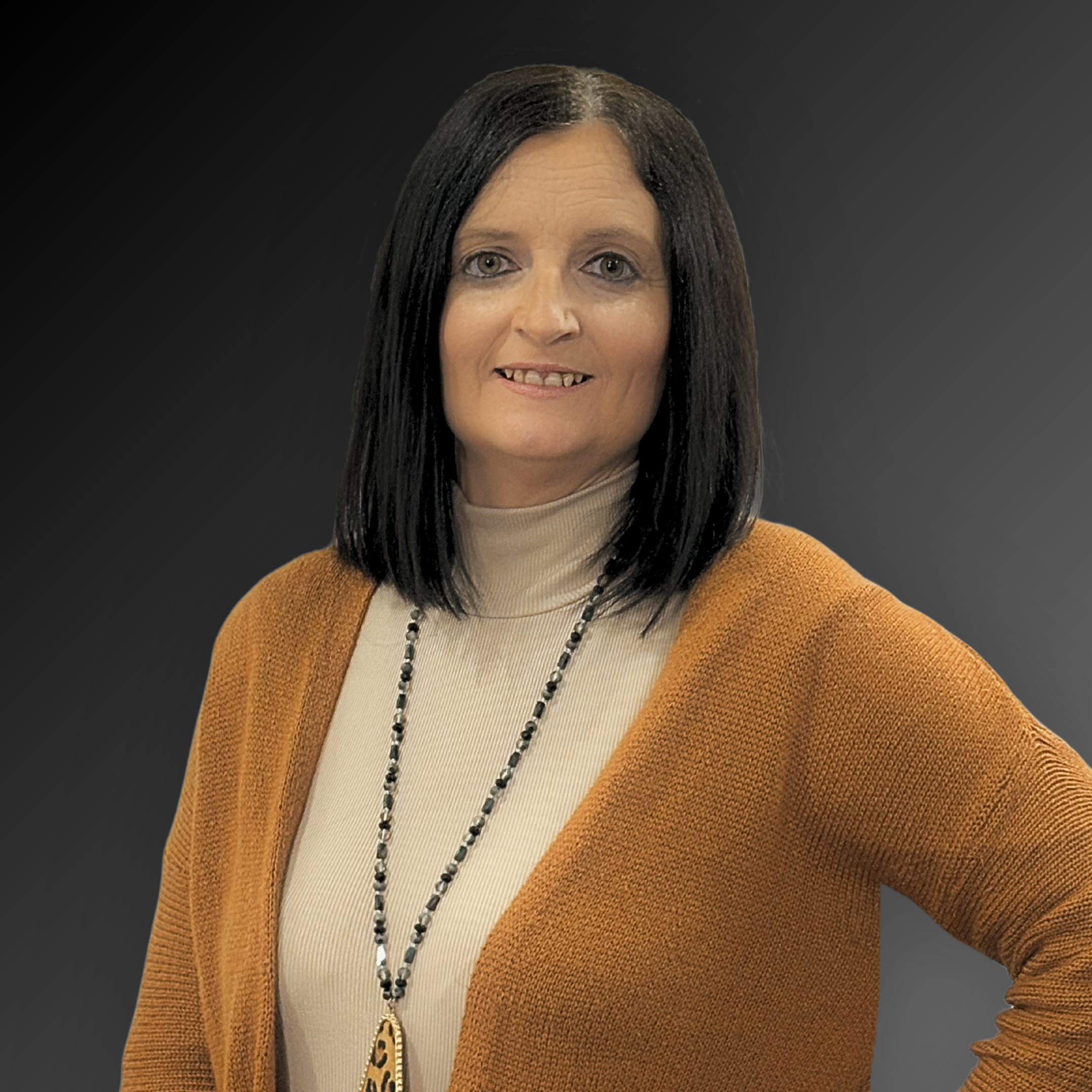 Headshot image of Ashley Smith in orange cardigan and dark grey background