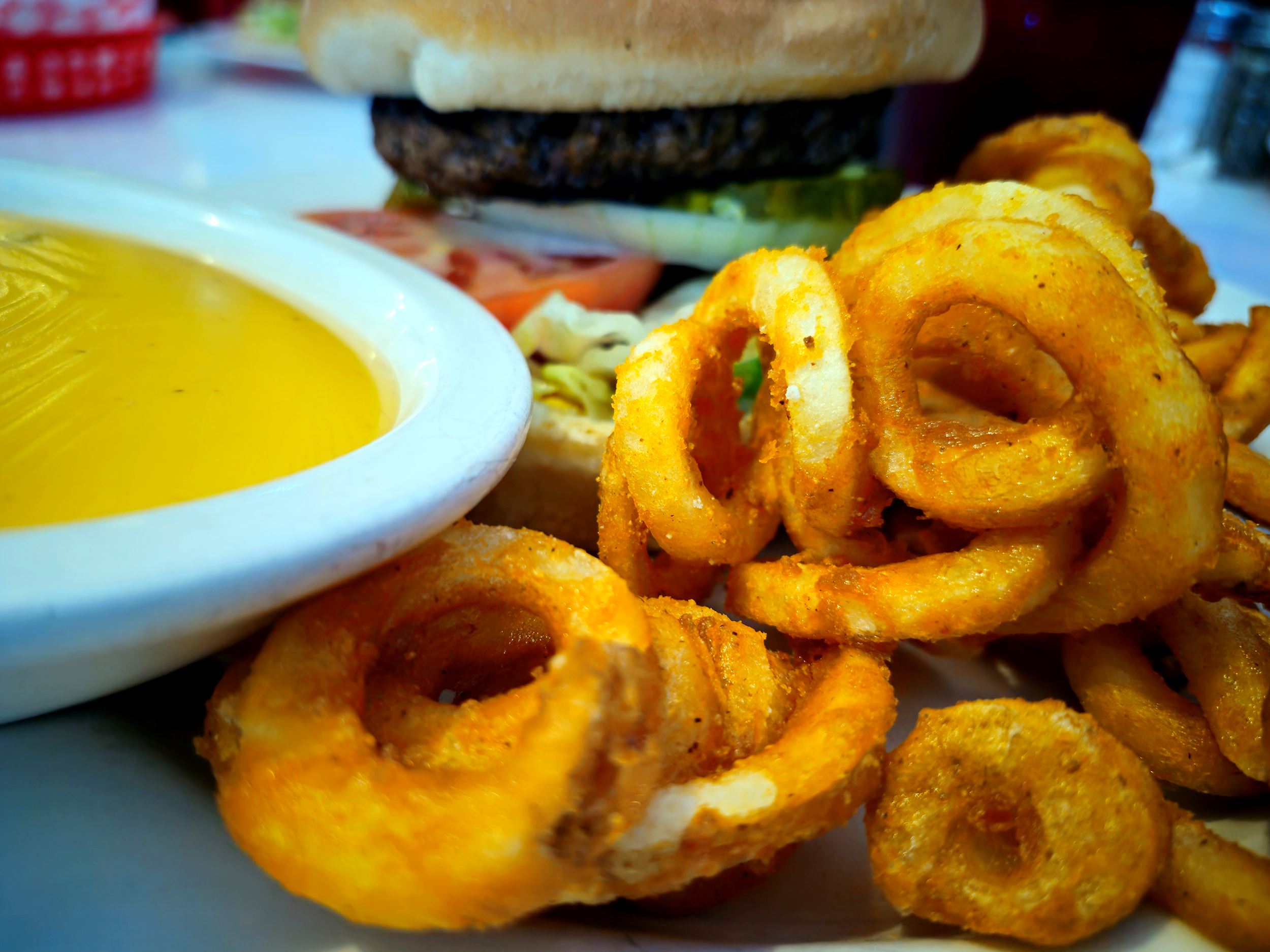 Curly fries and queso sauce in front of a 1/2 pound fresh burger at Hot Rodz Diner