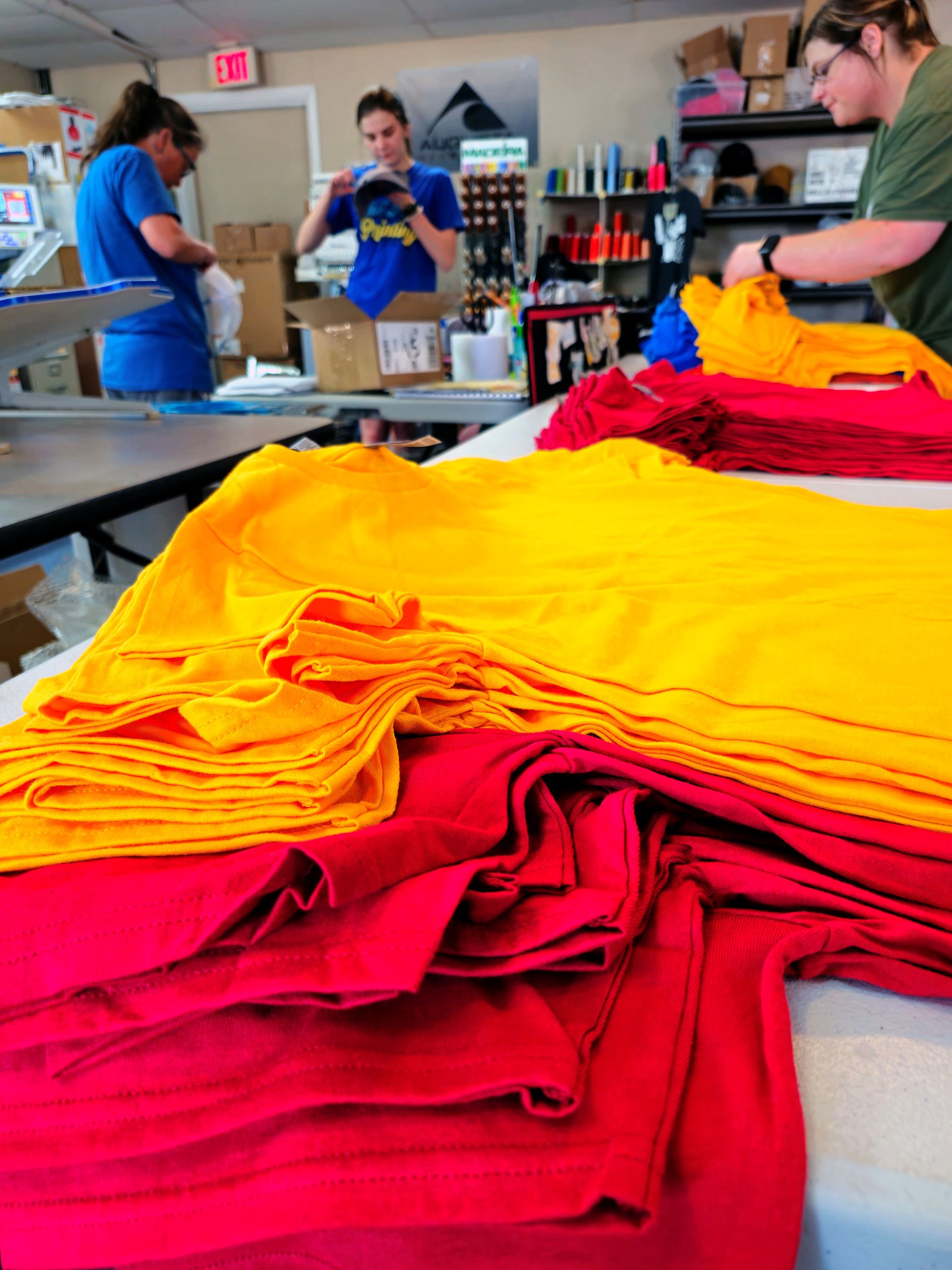 Stacks of t-shirts with employees working the background
