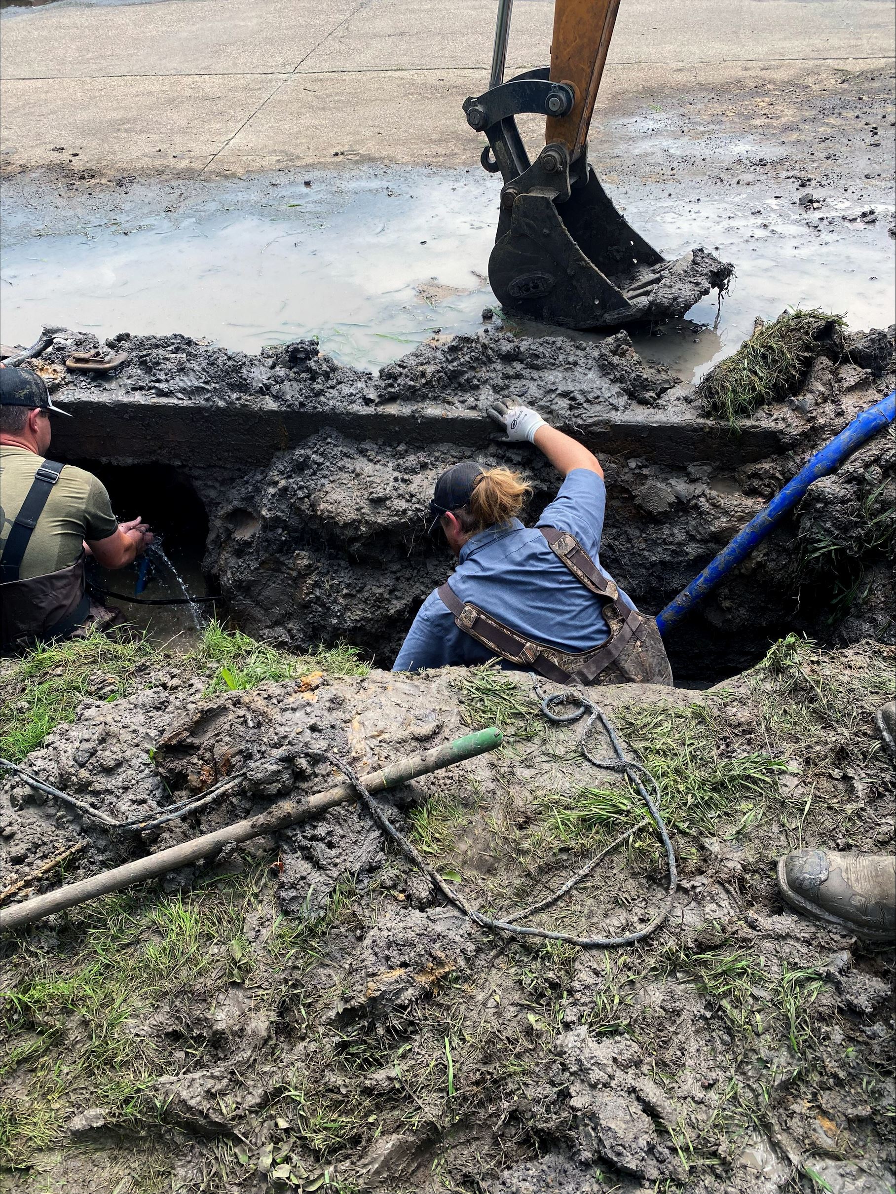 Public Works employees working in a hole to fix a pipe